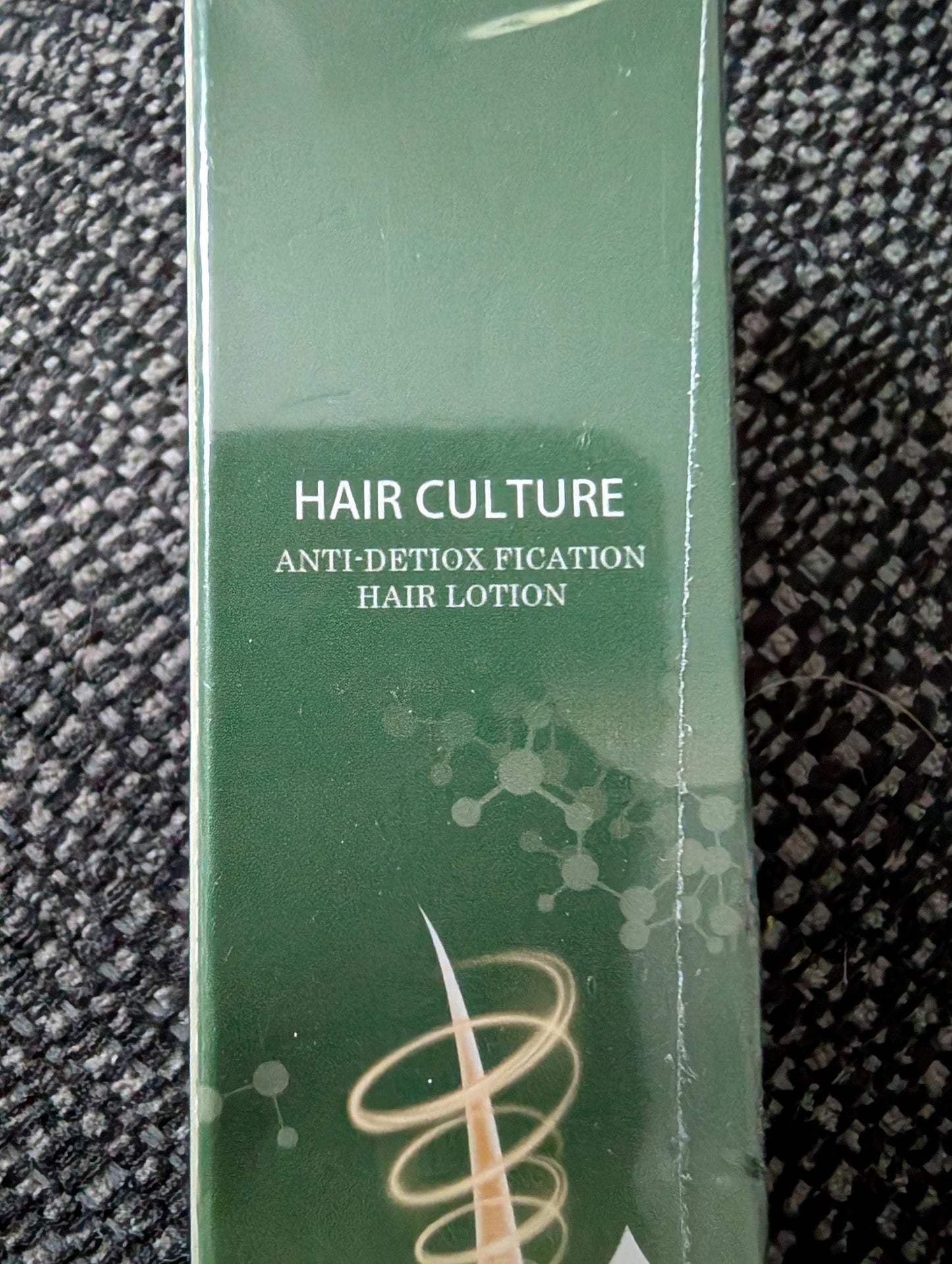 Green bottle of 'Hair Culture Anti-Detoxification Hair Lotion' on a textured black surface