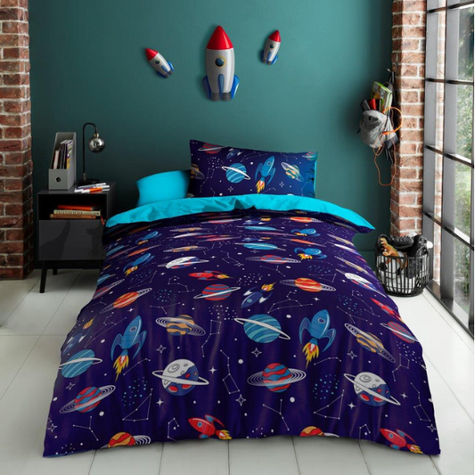 Space-themed bedding set with rockets and planets on a blue comforter in a room with brick walls and a window.