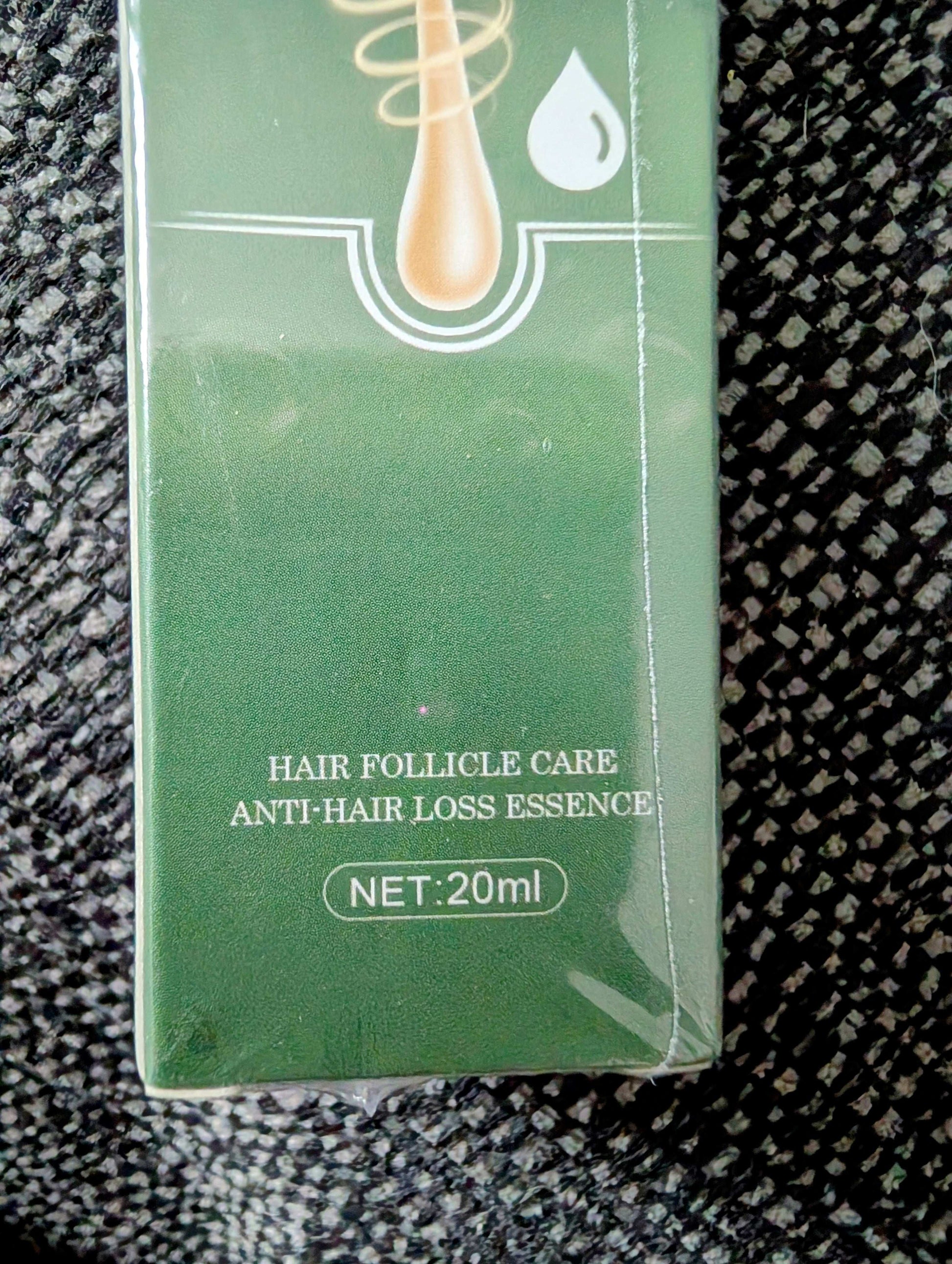 Green box of hair follicle care and anti-hair loss essence on a textured surface