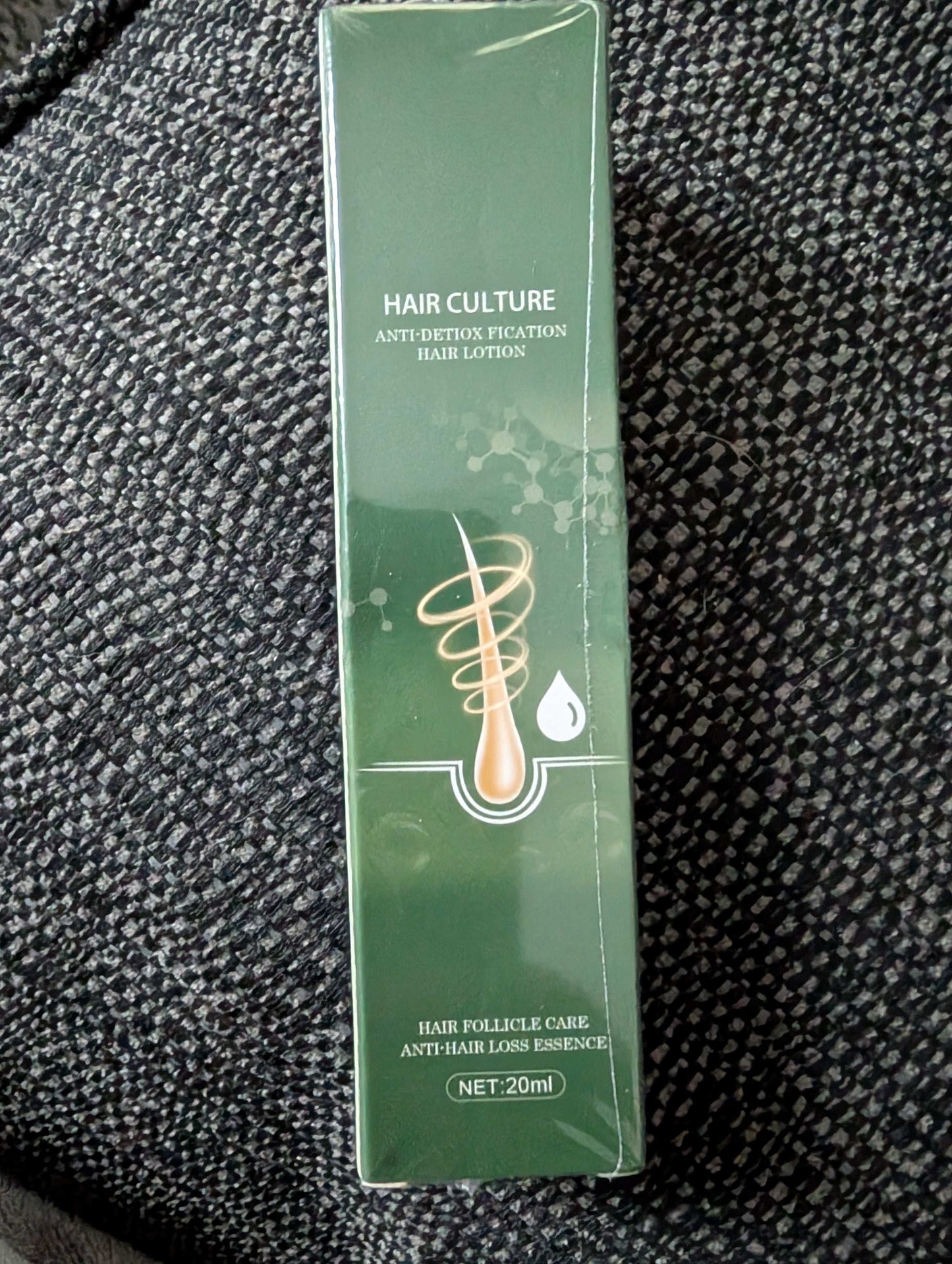 Green hair care product box on a textured black surface