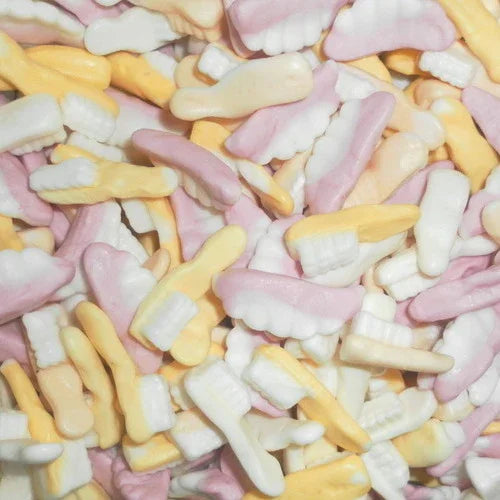 Close-up of fruity Swizzels foam sweets shaped like toothbrushes and teeth in pink, white, and yellow hues